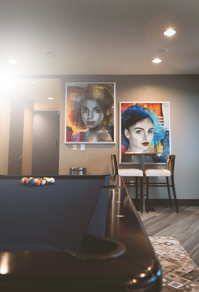 Game room with pool table and colorful portrait artwork above a bar-height seating area