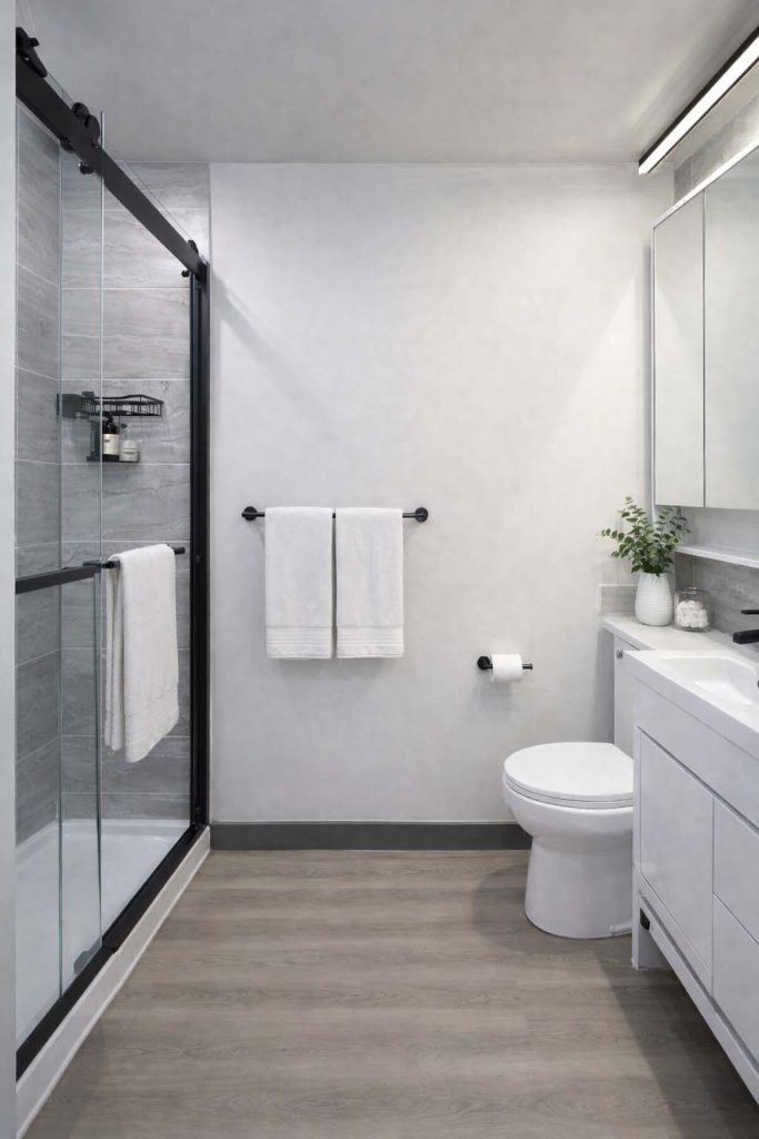 Bathroom with sliding glass shower door, wood-look flooring, white vanity, and modern black fixtures
